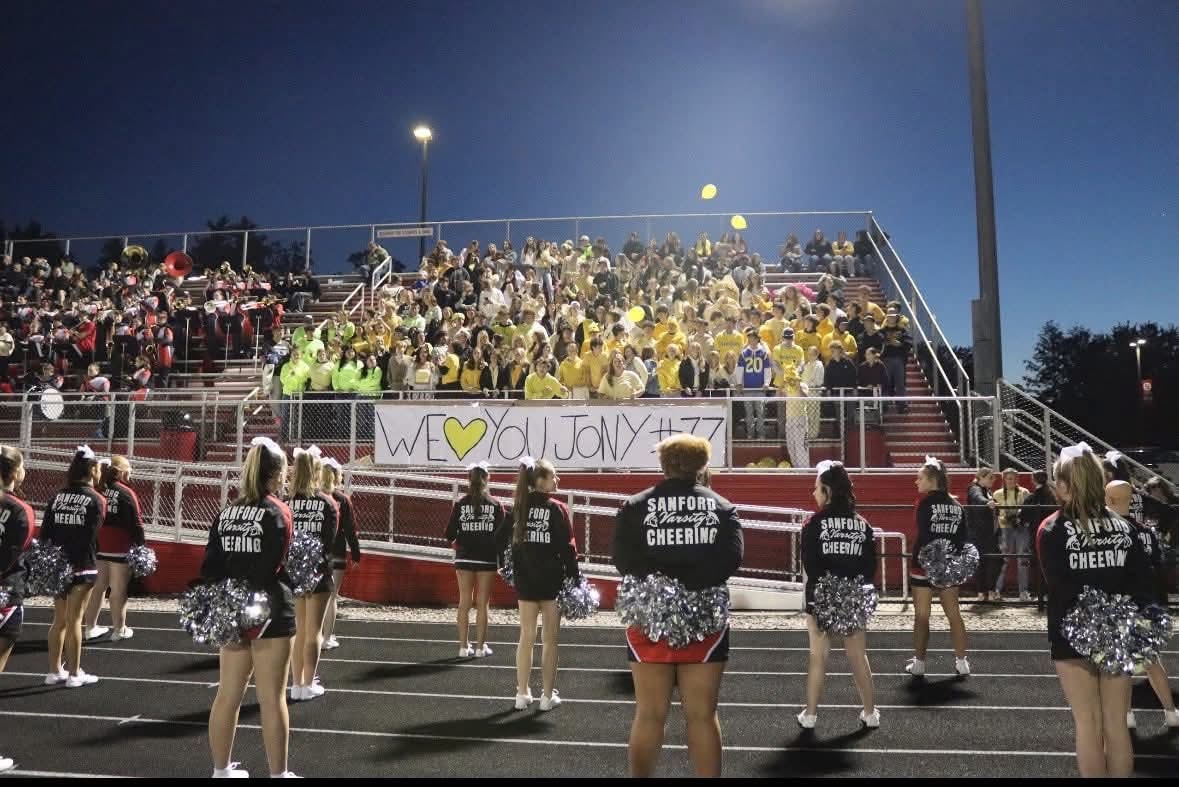 Sanford youth sports community honoring Jony with a “We Love You Jony #77” banner at a football game